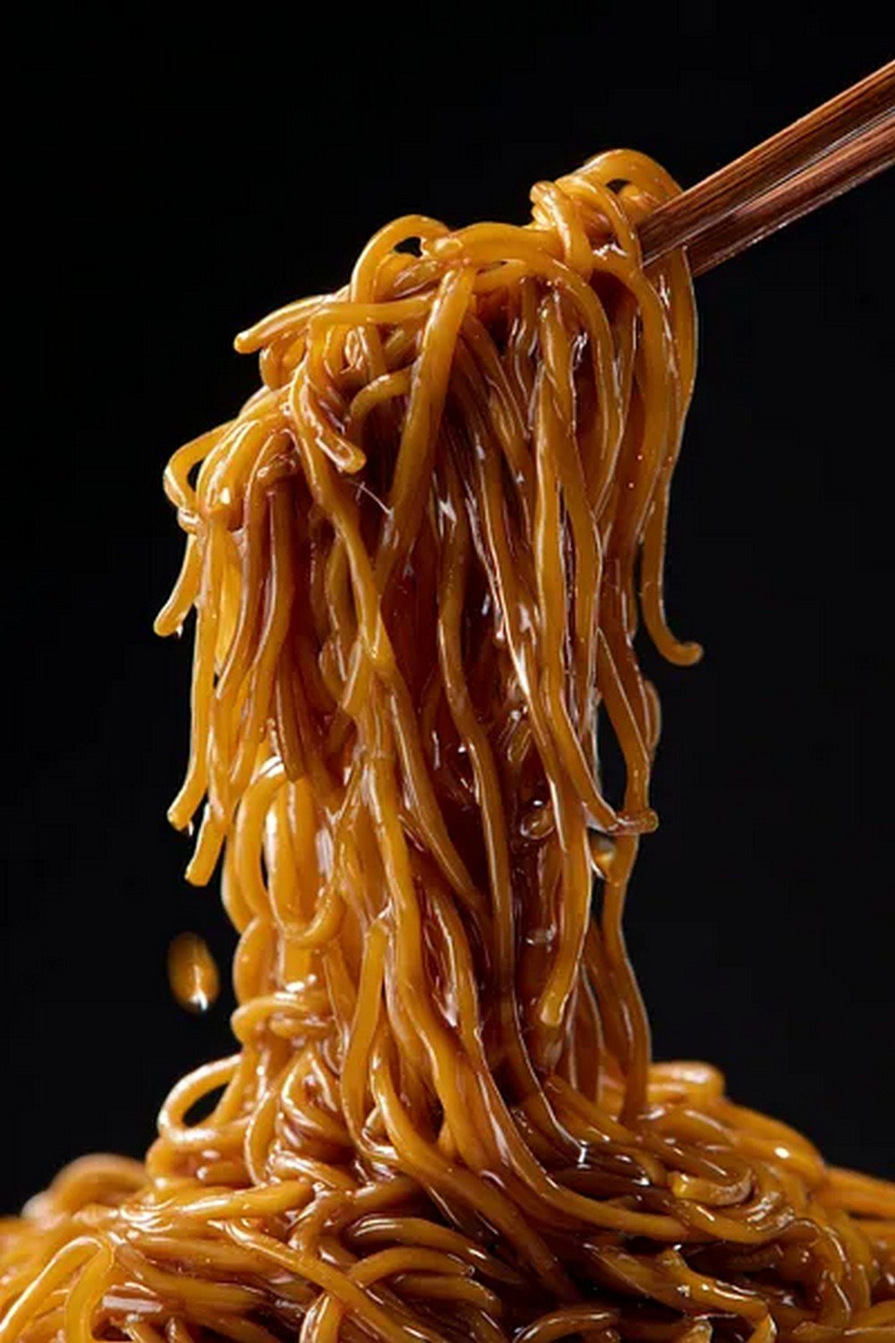 chopsticks lifting lo mein noodles with sauce
