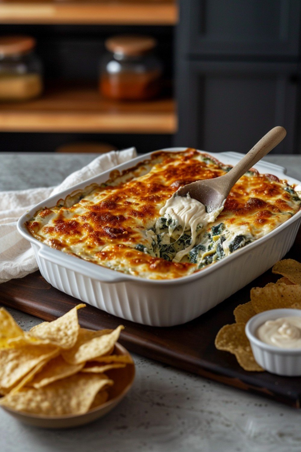 Homemade Applebee's Spinach Artichoke Dip in baking dish with tortilla chips on wooden board in warm home kitchen game day scene
