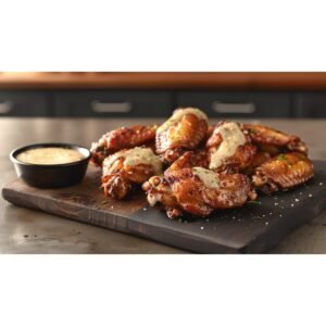 Buffalo Wild Wings Garlic Parmesan sauce copycat — creamy pale ivory garlic sauce with herb specks drizzled over golden wings
